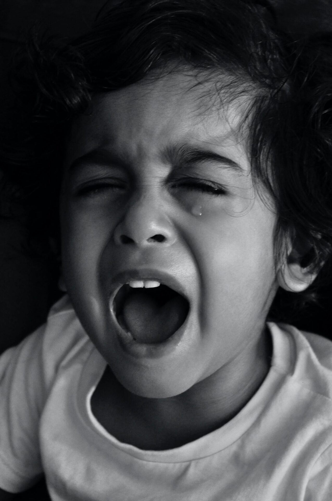 black and white photo of a child crying with their mouth open