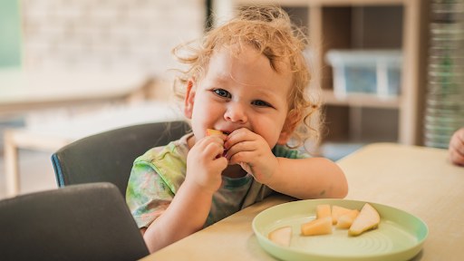 Toddler enjoying a healthy snack at Arden Early Learning Airlie Beach